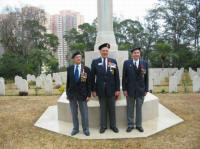 L to R: Aubrey Flegg(WG), Larry Stebbe(WG) and John Lowe(RRC) standing in front of the Stone of Remembrance at Sai Wan Cemetery 